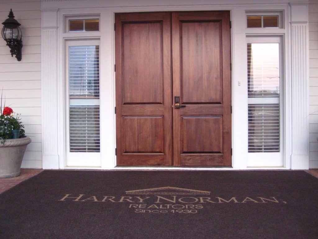 Harry Norman has a big welcome for home buyers with an oversize walnut custom logo floor mat warmly greeting everyone